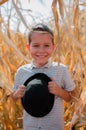 Happy smiling boy. Cute young 10 year old boy with black hat in his hands. Child in hte corn field - harvest season