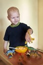 A happy smiling boy feeds a toy dinosaur porridge from a spoon Royalty Free Stock Photo