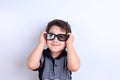 Happy smiling boy looking through sunglasses, studio shoot on wh Royalty Free Stock Photo