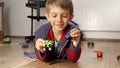 Happy smiling boy playing with his toys and cars while lying on floor in bedroom Royalty Free Stock Photo