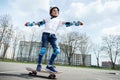 Happy and smiling boy in protective gear and helmet keeps balance while riding a skateboard Royalty Free Stock Photo