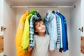 Preteen boy chooses clothes in the wardrobe closet at home. Kid hiding among clothes in wardrobe Royalty Free Stock Photo