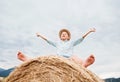 Happy smiling boy sits astride on the haystack