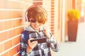 Happy smiling boy with smartphone playing game outside, over brick wall. New generation, leisure, children, technology. Schoolboy Royalty Free Stock Photo