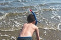 Happy and smiling boy in the snorkeling mask and tube on the sand on the beach.