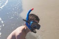 Happy and smiling boy in the snorkeling mask and tube on the sand on the beach.