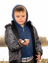 A happy smiling boy is standing on the bank of the river and holding a fish in his hands. The boy caught a fish. Autumn fishing