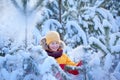 Happy smiling boy in winterwear walking in snowy winter forest. Child play outdoors in snow