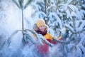Happy smiling boy in winterwear walking in snowy winter forest. Child play outdoors in snow