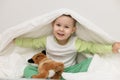 Happy smiling boy 3 years old hiding under the covers sitting on the bed, daily routine, put the child to sleep Royalty Free Stock Photo