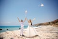 Happy smiling bride and groom hands releasing white doves on a sunny day. Mediterranean Sea. Cyprus Royalty Free Stock Photo