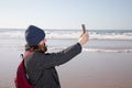 happy smiling brunette middle aged woman make picture selfie smartphone in sea coast beach winter portrait Royalty Free Stock Photo