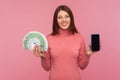 Happy smiling brunette woman holding fun of euro banknotes and cell phone with empty display in hands, mobile banking application Royalty Free Stock Photo
