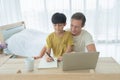 Happy smiling business blonde, man. Freelance working from home and his son, student teaching homework online with laptop computer Royalty Free Stock Photo