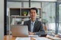 Happy smiling business man company executive ceo manager wearing suit sitting at desk in office working on laptop Royalty Free Stock Photo