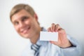 Happy smiling business man showing blank businesscard and dreaming, while leaning on wall at office Royalty Free Stock Photo