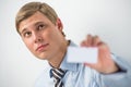 Happy smiling business man showing blank businesscard and dreaming, while leaning on wall at office Royalty Free Stock Photo