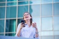 Happy smiling business woman talking on mobile smartphone and drinking coffee from disposable paper cup in the street with office Royalty Free Stock Photo