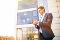 Happy smiling businessman wearing suit and using modern smartphone near office at early morning Royalty Free Stock Photo