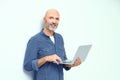 Happy smiling businessman work holding laptop leaned on a wall looking at camera wearing casual. Freelancer man work on Royalty Free Stock Photo