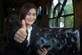 Happy smiling businesswoman with thumbs up gesture looking at camera sitting on a sofa Royalty Free Stock Photo