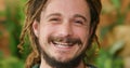 Happy, smiling and carefree hippie man standing outside against a nature background. Closeup face and head of stressless