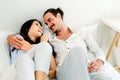 Happy smiling Caucasian couple lying on a comfy bed, relaxing and looking each other in the eyes and smiling. Romantic couple. Royalty Free Stock Photo