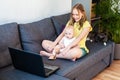 Happy smiling caucasian preteen girl with her cute infant sister chatting online using laptop for video call. Royalty Free Stock Photo