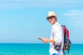 Happy smiling caucasian tourist asian young man looking passport with camera on the beach. Royalty Free Stock Photo