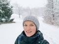 Happy smiling Caucasian woman taking selfie photo on smartphone in park outdoors on winter day.  Heavy snowfall and snowstorm. Royalty Free Stock Photo