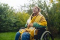 Happy smiling cheerful Caucasian girl on a wheelchair relaxing alone in autumn garden park Royalty Free Stock Photo