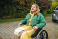 Happy smiling cheerful Caucasian girl on a wheelchair relaxing alone in autumn garden park Royalty Free Stock Photo