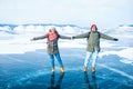 Happy smiling cheerful couple male and female holding each other's hands while standing together on frozen Baikal lake