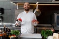 Happy smiling chef prepares meat dish with various vegetables in the kitchen. In one hand the man holds vegetables, in the other a Royalty Free Stock Photo