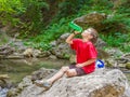 Happy smiling child boy drinking water on forest river back Royalty Free Stock Photo