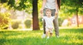 Happy smiling child boy makes first step in park, mom helps Royalty Free Stock Photo