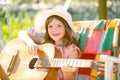 Happy smiling child girl play the guitar. Kids music and songs. Smiling child playing outdoors in summer. Royalty Free Stock Photo