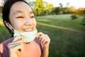 Happy smiling child girl is standing,taking off mask in green nature,breathe deep,woman enjoy breathing fresh air,relaxing in park Royalty Free Stock Photo