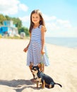 Happy smiling child little girl and dog walking on beach in summer Royalty Free Stock Photo