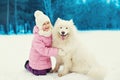 Happy smiling child playing with white Samoyed dog on snow in winter Royalty Free Stock Photo