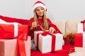 Happy smiling child wearing Santa Claus hat opening Christmas present while sitting on sofa at home  Merry Christmas and Holidays Royalty Free Stock Photo
