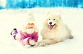 Happy smiling child and white Samoyed dog lying on snow winter day Royalty Free Stock Photo