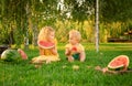 Happy smiling children eating watermelon outdoors on picnic in summer at sunset. White blonde baby boy and girl, sister and Royalty Free Stock Photo