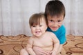Happy smiling children portrait. Siblings - boy holding little baby girl, together sitting home
