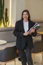 Happy smiling of confident businesswoman jacket holding laptop and a stack of papers of a cafe