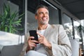 Happy mid aged business man sitting in outdoor office using cell phone. Royalty Free Stock Photo