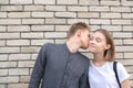 Happy smiling couple against the background of a brick wall, a young man kisses a girl on her cheek, she smiles Royalty Free Stock Photo