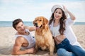 Happy smiling couple in love sitting on beach with dog Royalty Free Stock Photo