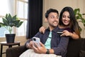 Happy smiling couple making online purchase by talking eachother on mobile phone by using credit card at home - concept Royalty Free Stock Photo