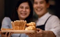 Happy Smiling Couple Presenting some Fresh Bread on Wooden Tray. Bake at Home. Closeup